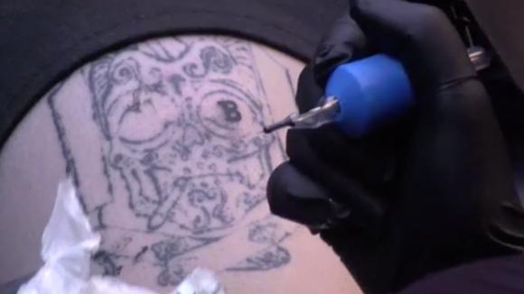 Dylan laat een bitcoin tatoeage zetten ter promotie van de opening voor de tattoo shop